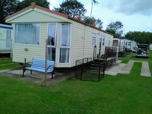 a small house with a blue bench in the grass at Caravan hire Winthorpe Skegness in Skegness