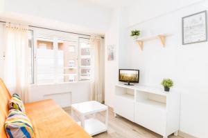 ein weißes Wohnzimmer mit einem TV und einem Fenster in der Unterkunft Suite Homes Malagueta Beach in Málaga