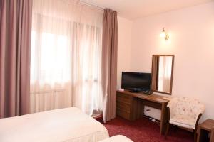 a hotel room with a television and a desk with a mirror at Hotel Gema in Braşov