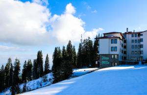 un edificio en una colina cubierta de nieve con árboles en Aparthotel Pine Hills Pamporovo en Pamporovo