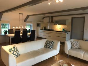 uma sala de estar com um sofá branco e uma cozinha em vakantiewoning grensgebied Groningen/Drenthe/Friesland em Zevenhuizen