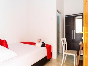 RedDoorz near Cipinang Indah Mall في جاكرتا: غرفة نوم صغيرة بها سرير وكرسي