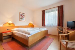 a bedroom with a bed and a desk and a television at Haus Peskoller in Perca