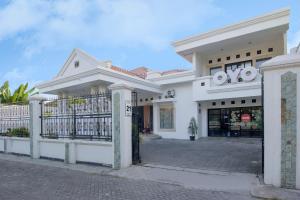 a white building with a gate in front of it at Collection O Aliya Homestay Yogyakarta in Yogyakarta