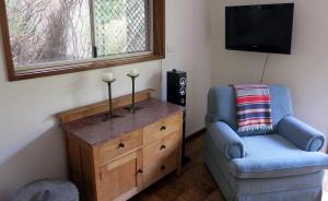 ein Wohnzimmer mit einem Stuhl, einer Kommode und einem TV in der Unterkunft A2@Port Willy in Port Willunga