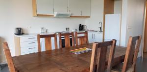 a kitchen with a wooden table and chairs and a kitchen with a refrigerator at Bifröst Apartments in Bifrost