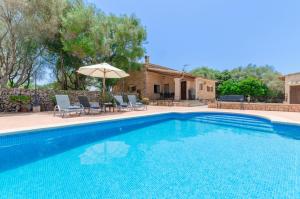 a swimming pool with chairs and an umbrella next to a house at Son Garbi in Algaida