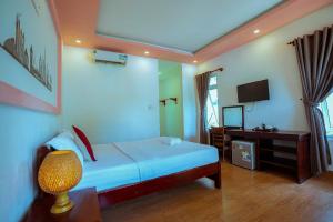 une chambre avec un lit, une télévision et une lampe dans l'établissement Long Mountain Resort, à Duong Dong