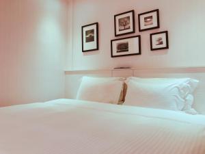 a bedroom with a white bed with three pictures on the wall at Wemeet Hotel in Pingtung City
