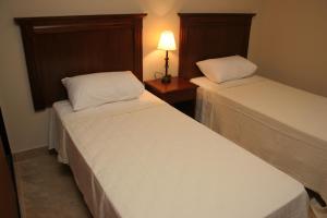 2 camas en una habitación de hotel con una lámpara en una mesa en Inter Apart Hotel en Salta