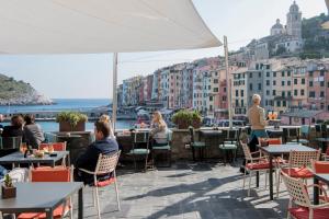 a group of people sitting at tables on a patio at Grand Hotel Portovenere in Portovenere