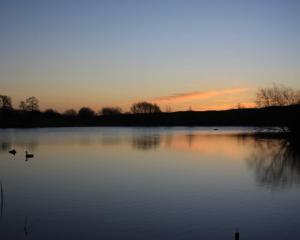 a lake with two ducks in the water at sunset at Cherry Orchard Farm in Bath