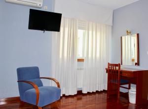 a living room with a chair and a desk and a television at Hotel As Camelias in Vilarrodis