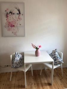 a white table and chairs with a vase of flowers on it at Modern CITY Apartments in Kaiserslautern