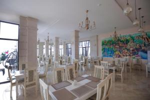 a dining room with tables and chairs and a mural at Black Sea Riviera Hotel in Shekvetili