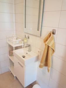 a white bathroom with a sink and a mirror at Apartment ALMA - to travel is to live in Celje