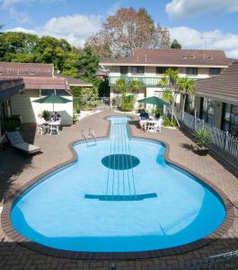 a large swimming pool in a courtyard with a building at Dukes Midway Lodge in Auckland
