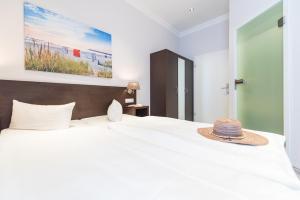 ein Schlafzimmer mit einem großen weißen Bett mit Hut darauf in der Unterkunft Hotel Villa Belvedere in Binz