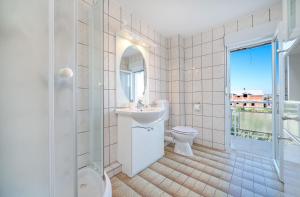 La salle de bains blanche est pourvue d'un lavabo et de toilettes. dans l'établissement Apartmani Patača, à Vodice