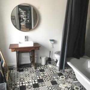La salle de bains est pourvue d'un miroir et de carrelage noir et blanc. dans l'établissement Cottage familial, à Ozeville