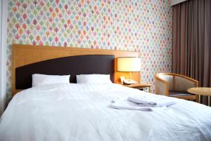 a bedroom with a white bed and a table with a lamp at Hotel Wing International Tomakomai in Tomakomai