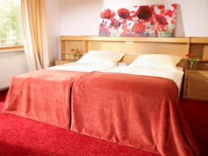 a bedroom with a bed with a red blanket on it at Berghotel Wintersberg in Bad Ems