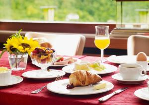 einen Tisch mit Teller mit Lebensmitteln und ein Glas Orangensaft in der Unterkunft Berghotel Wintersberg in Bad Ems