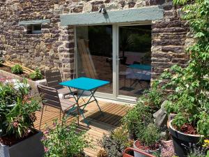 eine Terrasse mit einem Tisch und Stühlen auf einer Holzterrasse in der Unterkunft La maison des Légendes in Paimpont