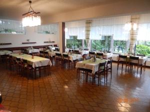 uma sala de jantar com mesas, cadeiras e janelas em Parkhotel Zuzek em Sankt Kanzian