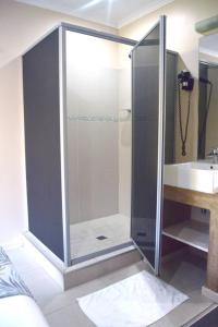 a glass shower in a bathroom with a sink at Essenwood Park Hotel in Durban