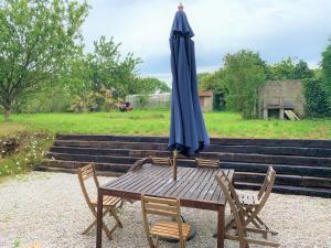 un tavolo in legno con ombrellone e sedie blu di Cottage familial a Ozeville