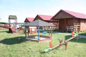 a playground with a sandbox and a building with a tent at Domki u Karasia in Rusinowo