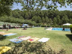a group of people laying on the grass near a pool at La Calleja in Villarejo del Valle