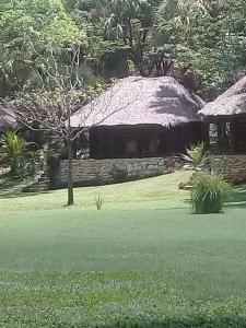 a stone building with a grass roof on a field at Cabañas Sierraverde Huasteca Potosina in Tamasopo