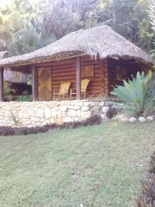 a log cabin with a thatch roof and a stone wall at Cabañas Sierraverde Huasteca Potosina in Tamasopo
