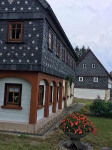 a house with a black roof with flowers in the yard at Ferienwohnung Schulze Jonsdorf in Kurort Jonsdorf