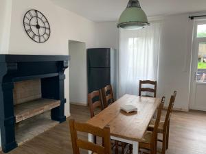 a dining room with a table and a clock on the wall at Cottage familial in Ozeville