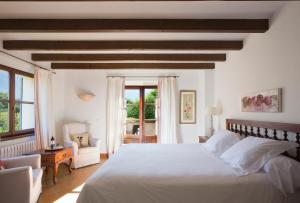 a bedroom with a large white bed and a chair at Finca Ca'n Quatre in Sóller