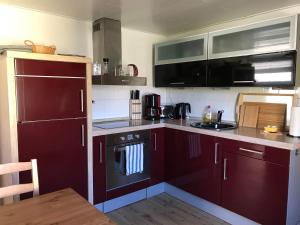 een keuken met rode kasten en een fornuis met oven bij Alte Schmiede Sagard in Sagard