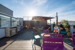 马德里Safestay Madrid Central的两名女性坐在带紫色椅子的屋顶露台上