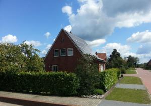 een rood bakstenen huis met een metalen dak bij Haus Bramland --- 2 FeWo's --- EG 60qm und OG 55qm in Haselünne