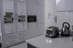 una cocina con armarios blancos y tetera en una encimera. en iTowers Studio Suite, en Gaborone