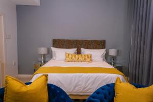 a bedroom with a large bed with two blue chairs at iTowers Studio Suite in Gaborone