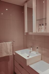 La salle de bains est pourvue d'un lavabo blanc et d'un miroir. dans l'établissement iTowers Studio Suite, à Gaborone