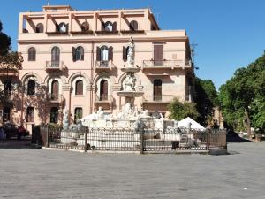 a large pink building with a fountain in front of it at Il galleone in Messina