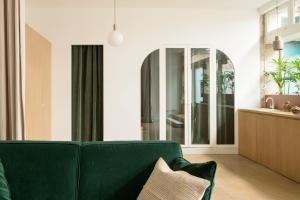 a living room with a green couch and a mirror at Joie Paris St Germain-des-Prés - Bon Marché in Paris