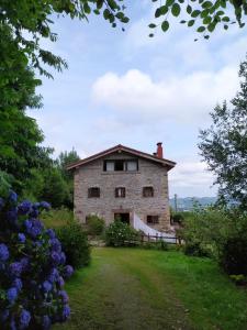 una vieja casa de piedra en una colina con flores en Casa Rural Haitzetxea, en Zugarramurdi
