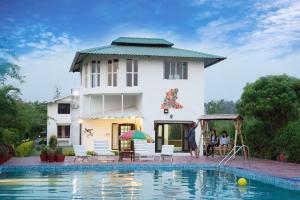 a villa with a swimming pool in front of a house at Corbett Treat Resort in Rāmnagar