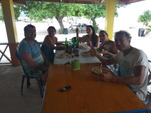 a group of people sitting around a wooden table at Ocean holiday in Bira