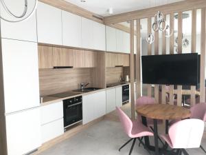 una cucina con armadi bianchi, tavolo e sedie rosa di Apartament the Good Place a Brodnica